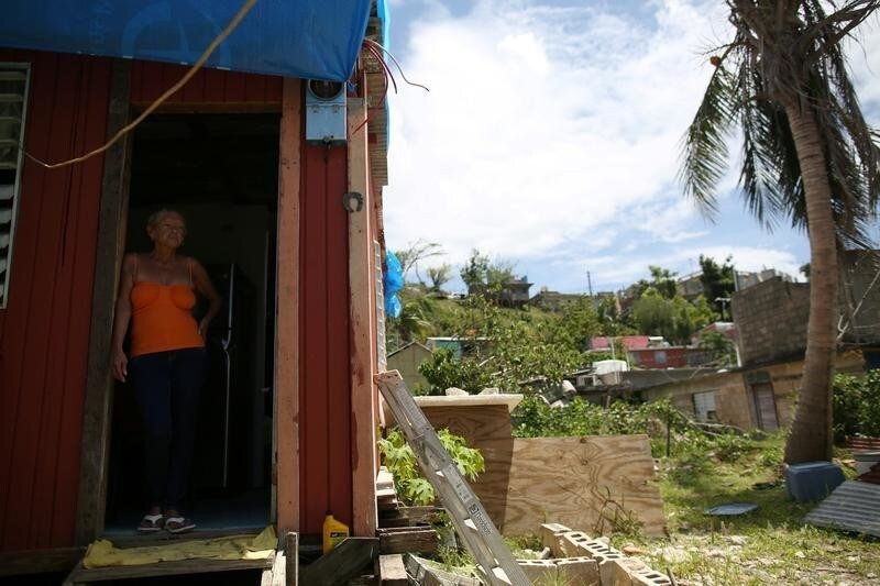 Bexaida Torres stands in the door of what is left of her home after Hurricane Maria hit the island in September, in a neighbourhood in Canovanas, Puerto Rico April 10, 2018. REUTERS/Alvin Baez - RC15BD2E68C0