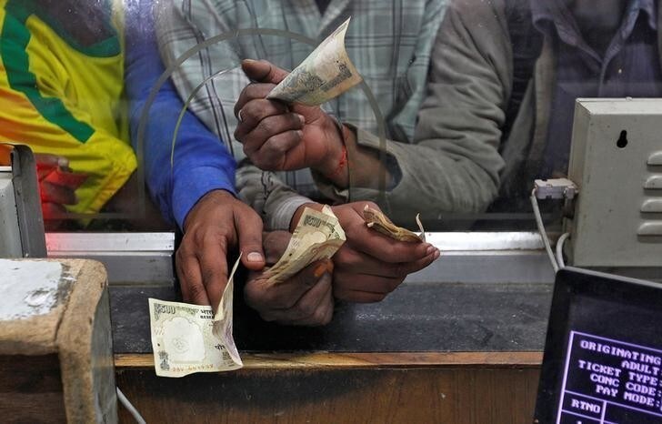 Passengers hold 500 (bottom) rupee banknotes to buy train tickets at a railway booking counter in Allahabad, India, November 9, 2016. REUTERS/Jitendra Prakash