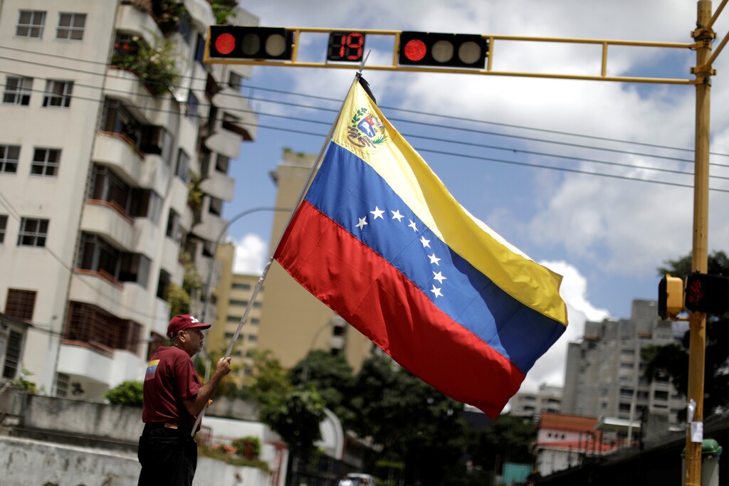 A man with a Venezuelan flag stands in a street after a strike called to protest against Venezuelan President Nicolas Maduro's government in Caracas, Venezuela, July 29, 2017. REUTERS/Ueslei Marcelino - RTS19OHZ
