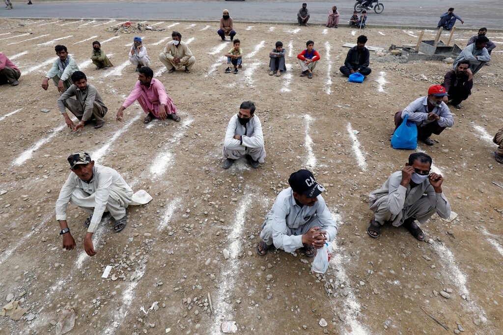 Men sit on the ground with lines drawn with chalk to maintain safe distance as they wait to receive sacks of ration handouts from a distribution point of a charity welfare during a partial lockdown after Pakistan shut all markets, public places and discouraged large gatherings amid an outbreak of coronavirus disease (COVID-19), in Karachi, Pakistan, March 26, 2020. Coronavirus china virus health healthcare who world health organization disease deaths pandemic epidemic worries concerns Health virus contagious contagion viruses diseases disease lab laboratory doctor health dr nurse medical medicine drugs vaccines vaccinations inoculations technology testing test medicinal biotechnology biotech biology chemistry physics microscope research influenza flu cold common cold bug risk symptomes respiratory china iran italy europe asia america south america north washing hands wash hands coughs sneezes spread spreading precaution precautions health warning covid 19 cov SARS 2019ncov wuhan sarscow wuhanpneumonia pneumonia outbreak patients unhealthy fatality mortality elderly old elder age serious death deathly deadly