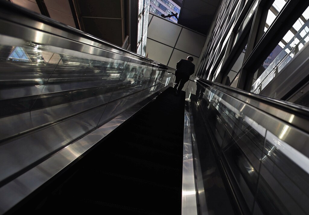 A man rides an escalator at Tokyo's business district December 8, 2014. Japan's economy shrank more than initially reported in the third quarter on declines in business investment, data showed on Monday, surprising markets and backing premier Shinzo Abe's recent decision to delay a second sales tax hike. REUTERS/Yuya Shino (JAPAN - Tags: BUSINESS) - RTR4H2EP