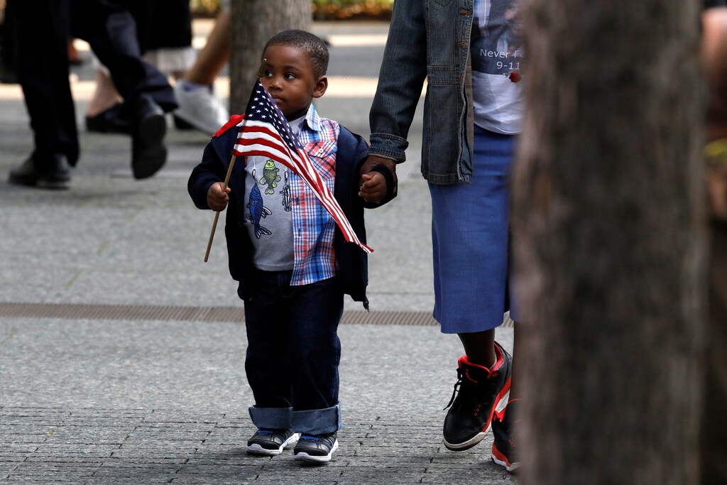 A young boy carries an American flag as people gather at the National 911 Memorial and Museum during ceremonies marking the 16th anniversary of the September 11, 2001 attacks in New York, U.S., September 11, 2017. REUTERS/Brendan McDermid - RC193B61E340