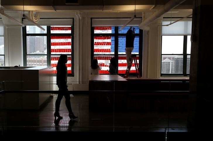 Employees create a U.S. flag image on a window with Post-it notes at the Horizon Media offices at 75 Varick Street in lower Manhattan, New York, U.S., May 18, 2016, where advertising agencies and other companies have started what is being called a "Post-it note art war" with employees in buildings across Canal street from each other creating colorful images in their windows with Post-it notes. REUTERS/Mike Segar