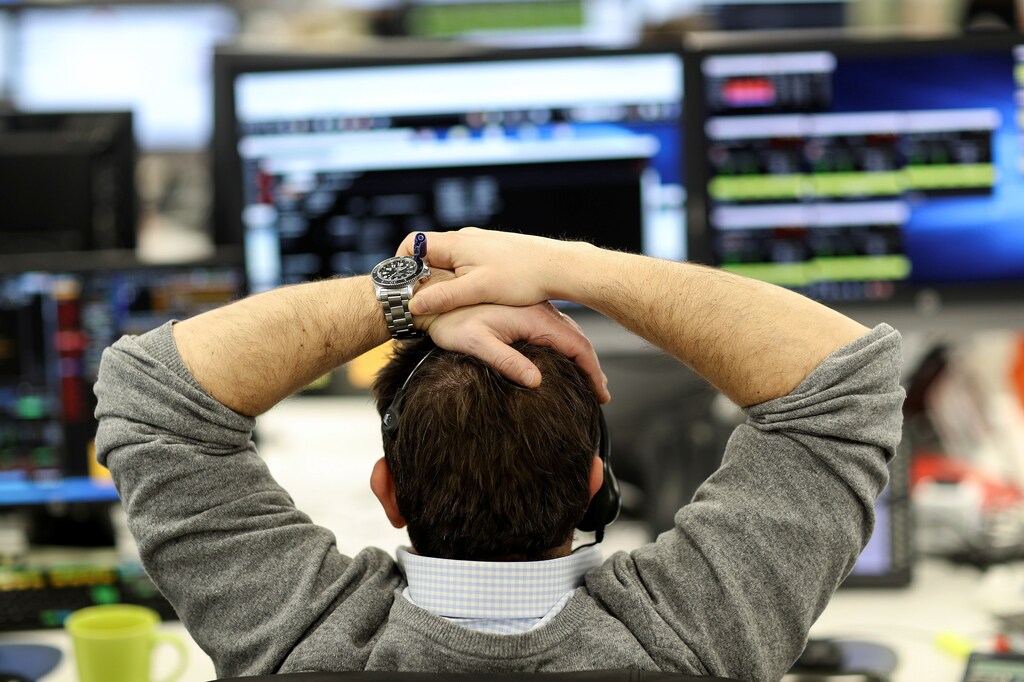 A broker looks at financial information on computer screens on the IG Index trading floor in London, Britain February 6, 2018. REUTERS/Simon Dawson - RC13323AD440