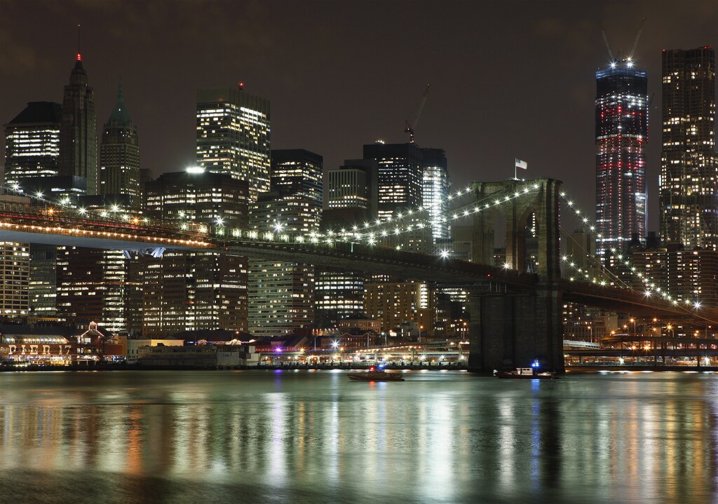 Emergency vessels inspect panelling hanging down from the bottom of the Brooklyn Bridge after it was struck by a crane passing underneath in New York March 13, 2012. REUTERS/Lucas Jackson (UNITED STATES - Tags: DISASTER TRANSPORT) - RTR2ZAVO