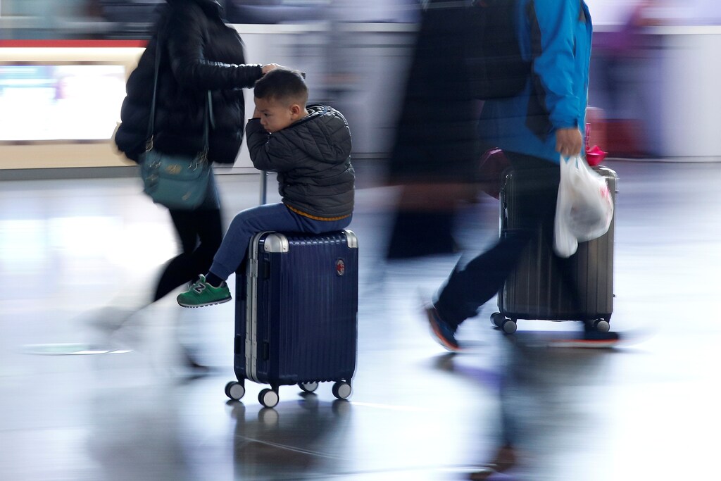 A person drags a suitcase as a boy clings to it at Shanghai's Hongqiao Railway Station as hundreds of millions of Chinese travel home for Lunar New Year in Beijing and Shanghai, in Shanghai, China January 25, 2017. REUTERS/Aly Song - RTSX87V