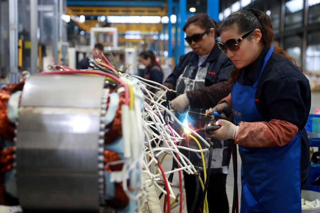 Women wearing sunglasses work at a production line manufacturing electric machine parts at a factory in Luan, Anhui province, China November 17, 2018. Picture taken November 17, 2018. REUTERS/Stringer ATTENTION EDITORS - THIS IMAGE WAS PROVIDED BY A THIRD PARTY. CHINA OUT. - RC11E1AB4D40