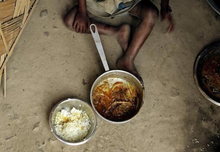 An Indian boy from a family of labourers that migrated from the state of Bihar prepares to eat on the banks of the Mahananda river in Siliguri, northeast India, March 10, 2005. India's liberalisation drive since 1991 has been felt more in cities than on the land, and disparities between urban rich and rural poor have grown. Some 260 million of India's billion-plus people live on less than $1 a day. According to estimates, several hundred thousand children work as labourers and beg on the streets in India. NO RIGHTS CLEARANCES OR PERMISSIONS ARE REQUIRED FOR THIS IMAGE. REUTERS/Desmond Boylan DB/jk