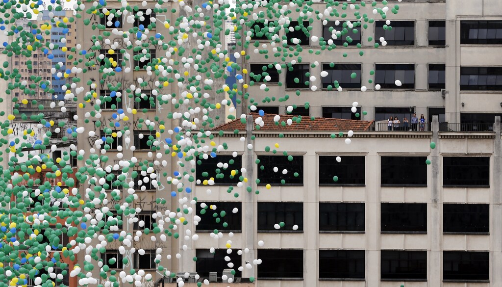 Residents watch from a building balloons are released into the skies above Sao Paulo downtown during year end celebrations December 30, 2013. REUTERS/Paulo Whitaker (BRAZIL - Tags: SOCIETY) - GM1E9CU1TA701