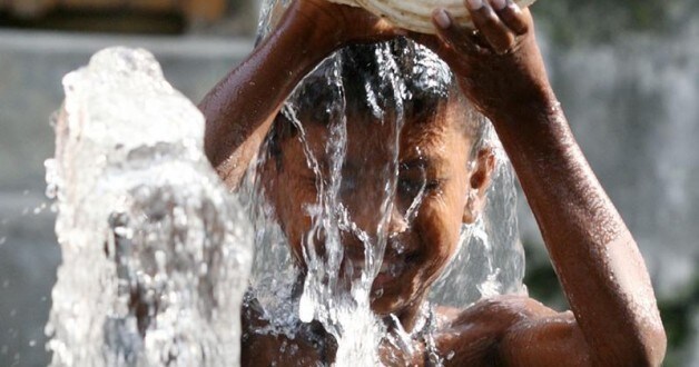 A boy pours water on himself for respite from the heat beside a roadside tap in Dhaka.