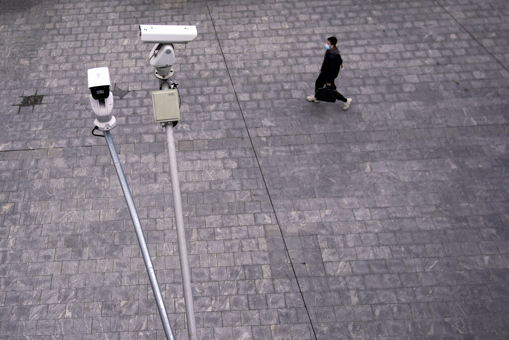 A man wearing a protective mask walks under surveillance cameras in Shanghai, China, as the country is hit by a novel coronavirus outbreak, at the Pudong financial district in Shanghai, China February 28, 2020. REUTERS/Aly Song - RC2L9F94G6TH