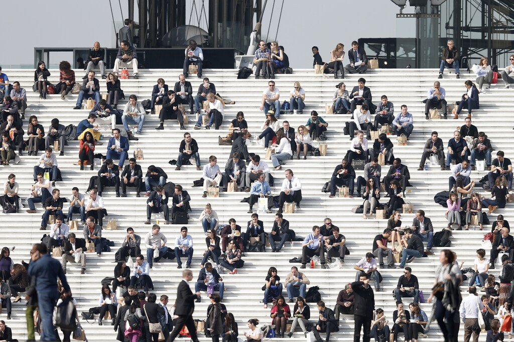 2014年3月13日，法国持续晴朗温暖的天气，商人们在巴黎西部金融商业区拉德芳斯凯旋门台阶上享受午餐时光。巴黎居民和游客沐浴在难得的阳光下，同时也饱受汽车尾气颗粒物污染之苦，本周巴黎的空气污染水平甚至超过了其他北欧首都城市。周四，包括巴黎在内的法国大片地区发布了空气污染最高警戒级别，促使巴黎当局宣布当天Velib自行车共享系统和Autolib电动汽车车队等绿色交通工具免费开放。路透社/Charles Platiau（法国 - 标签：商业、环境、社会）