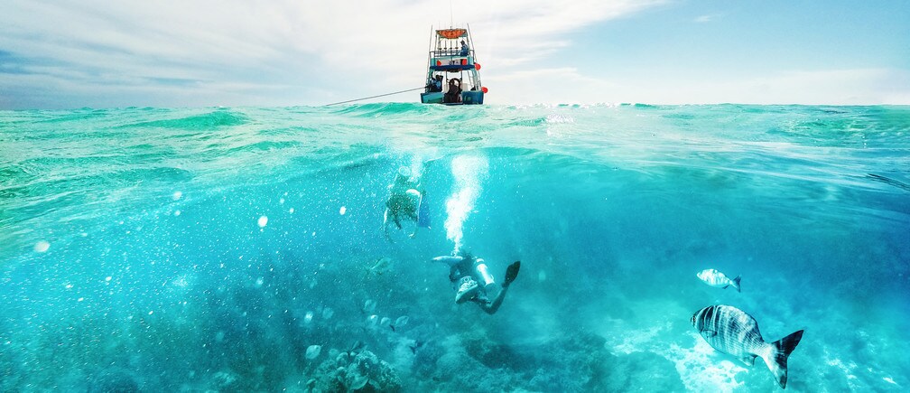 Buceador submarino y barco de pesca sobre el Mar Caribe en Cozumel, México