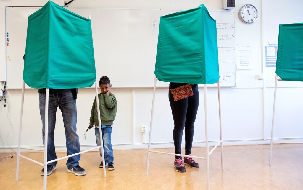 A child looks on as people stand in voting booths, in Malmo, Sweden September 9, 2018. TT News/Johan Nilsson via REUTERS ATTENTION EDITORS - THIS IMAGE WAS PROVIDED BY A THIRD PARTY. SWEDEN OUT. NO COMMERCIAL OR EDITORIAL SALES IN SWEDEN. - RC1F763E53C0