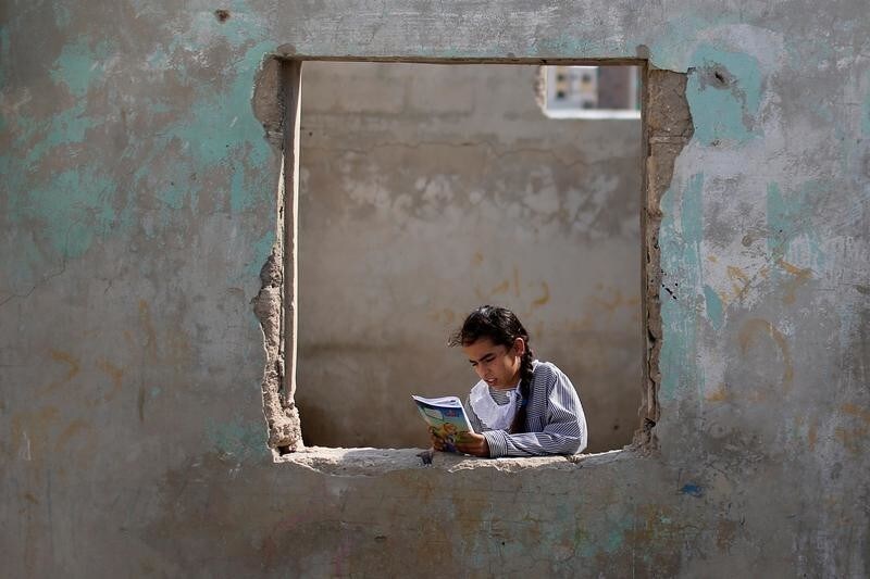 A Palestinian UNRWA schoolgirl holds her book as she stands by a window outside her family home in Al-Shati refugee camp in Gaza City October 23, 2019. Picture taken October 23, 2019. REUTERS/Mohammed Salem TPX IMAGES OF THE DAY - RC2N5D9JF9UC