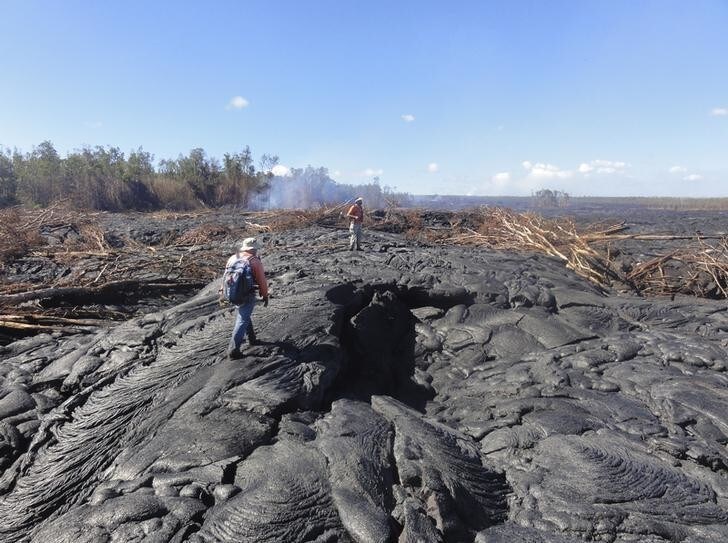 Hawaii Volcano Observatory (HVO) geologists walk over the surface of a lava flow from the Kilauea Volcano to track surface breakouts near the village of Pahoa, Hawaii October 22, 2014. The lava began flowing from the Kilauea Volcano on June 27 and as of October 24 the flow front was 0.7 miles (1.2 km) from Pahoa Village Road, according to the U.S. Geological Survey. About 4,000 people overall live in the residential communities that the lava is approaching. Picture taken October 22, 2014. REUTERS/U.S. Geological Survey/Handout (UNITED STATES - Tags: ENVIRONMENT DISASTER) THIS IMAGE HAS BEEN SUPPLIED BY A THIRD PARTY. IT IS DISTRIBUTED, EXACTLY AS RECEIVED BY REUTERS, AS A SERVICE TO CLIENTS. FOR EDITORIAL USE ONLY. NOT FOR SALE FOR MARKETING OR ADVERTISING CAMPAIGNS