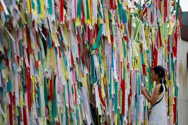 A girl looks at a barbed-wire fence decorated with ribbons bearing messages wishing for the unification between the two Koreas near the demilitarized zone separating the two Koreas in Paju, South Korea, August 10, 2017. REUTERS/Kim Hong-Ji TPX IMAGES OF THE DAY - RC1DEE456B70