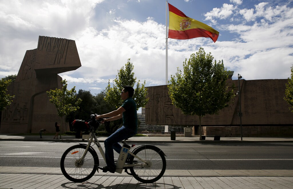 A man rides past Discovery Monument as a huge Spanish flag flutters in Madrid, Spain, August 6, 2015. Spanish Prime Minister Mariano Rajoy's ruling conservative Popular Party has taken a clear lead over rivals in a fragmented political landscape four months before a general election but looks set to fall far short of a majority to govern alone. REUTERS/Sergio Perez - GF20000015658