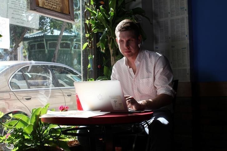 Reuters journalist Nick Brown works at his laptop at a cafe in San Juan, Puerto Rico, August 8, 2016. Picture taken August 8, 2016. REUTERS/Alvin Baez TO MATCH INSIGHT HEALTH-ZIKA/PATIENT
