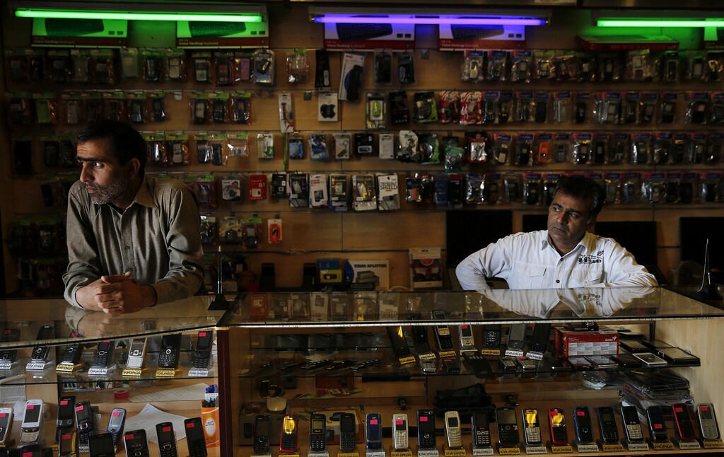 The owners of a mobile phone shop wait for customers in Marikana, Rustenberg April 2, 2014. Members of the Association of Mineworkers and Construction Union (AMCU) have downed tools at Lonmin, the main employer in the tough town of Marikana, and rivals Anglo American Platinum and Impala Platinum in a strike over wages, hitting 40 percent of global production. The 10-week strike, the biggest in South Africa's mines in living memory, has so far cost companies and workers a collective 17 billion rand ($1.60 billion) in revenue and wages, according to a tally updated constantly on an industry website. This has transformed bustling and crowded mining towns into ghost town-like skeletons of their former selves. Picture taken April 2. REUTERS/Siphiwe Sibeko (SOUTH AFRICA - Tags: BUSINESS CIVIL UNREST COMMODITIES TELECOMS) - GM1EA4418W201