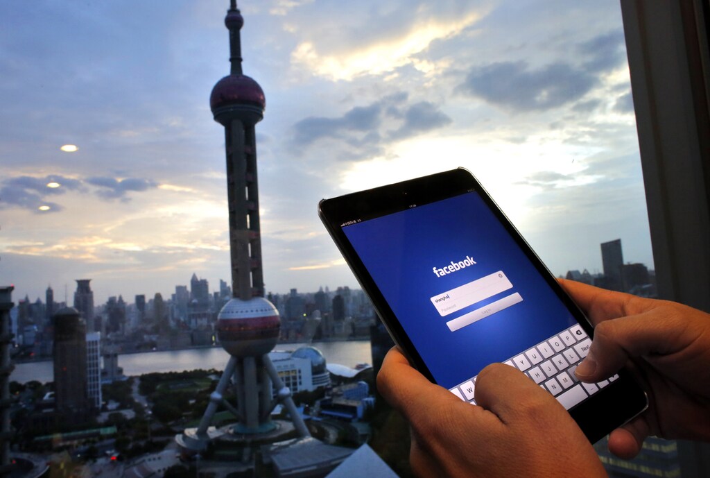 In this photo illustration, a man holds an iPad with a Facebook application in an office building at the Pudong financial district in Shanghai, September 25, 2013. Facebook Inc and Twitter face a daunting task in China, if access to their social networks is unblocked, as they would be up against deeply entrenched domestic rivals which cater to local needs and tastes. Access to Facebook and Twitter has been blocked in China since 2009, but will be lifted by the government in the Shanghai Free Trade Zone (FTZ) which is due to launch this weekend, the South China Morning Post reported on Tuesday - a move that has been popularly dubbed the "Internet Concession".