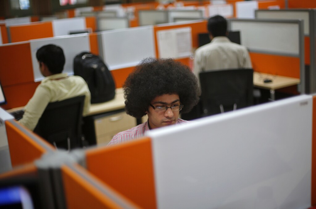 Employees work at their desks inside Tech Mahindra office building in Noida on the outskirts of New Delhi.