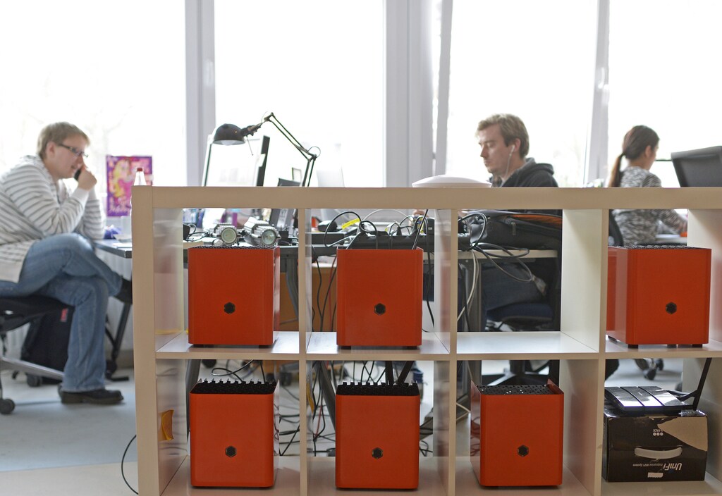 Employees sit at their desks behind Orange Protonet servers at the headquarter of German company Protonet in Hamburg, January 30, 2014. Protonet and many other start-ups in the country offer data security "made in Germany" after former U.S. National Security Agency contractor Edward Snowden alleged the NSA is engaged in industrial espionage and put software in almost 100,000 computers around the world. Picture taken January 30. TO GO WITH STORY DEUTSCHLAND-STARTUPS-NSA/ REUTERS/Fabian Bimmer (GERMANY - Tags: SCIENCE TECHNOLOGY BUSINESS TELECOMS) - RTX18AEY