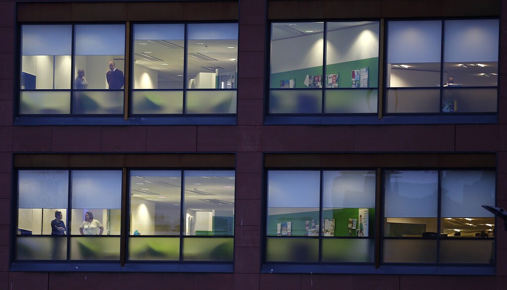 Workers look from the Rotherham Metropolitan Borough Council Offices in Rotherham, northern England, February 4, 2015. Rotherham's council leader and entire cabinet resigned after the publication of a report into their response to years of child sexual exploitation in the town. The report said the authority was not fit for purpose and had been in complete denial after an earlier inquiry found that 1400 children, some as young as 11, were abused in Rotherham, by gangs of predominantly Asian men. REUTERS/Darren Staples (BRITAIN - Tags: CRIME LAW POLITICS SOCIETY TPX IMAGES OF THE DAY) - LM1EB241E5601
