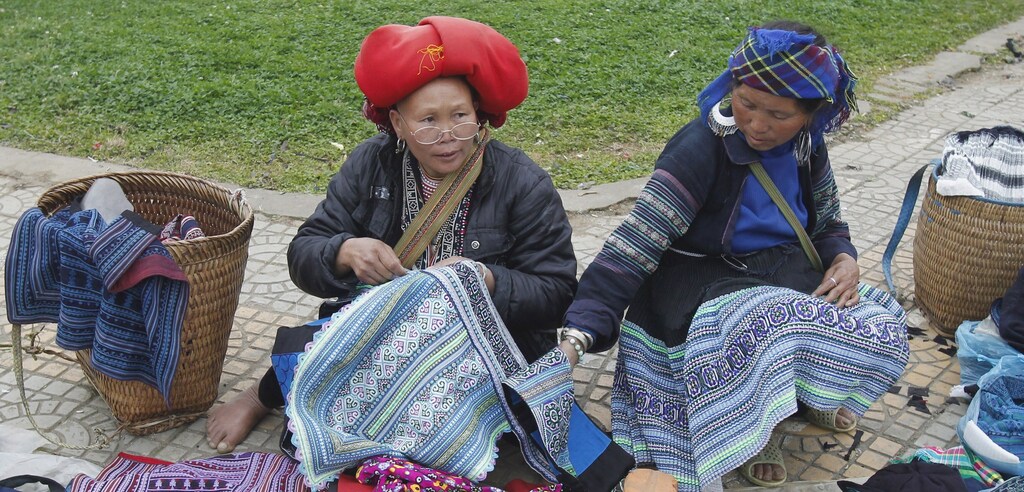 Ethnic Hmong (R) and Red Dao (L) women chat while displaying hand-made products for sale at a market at Sapa resort town in northern Lao Cai province, 350 km (217 miles) from Hanoi, Vietnam, Asia. March 15, 2013.