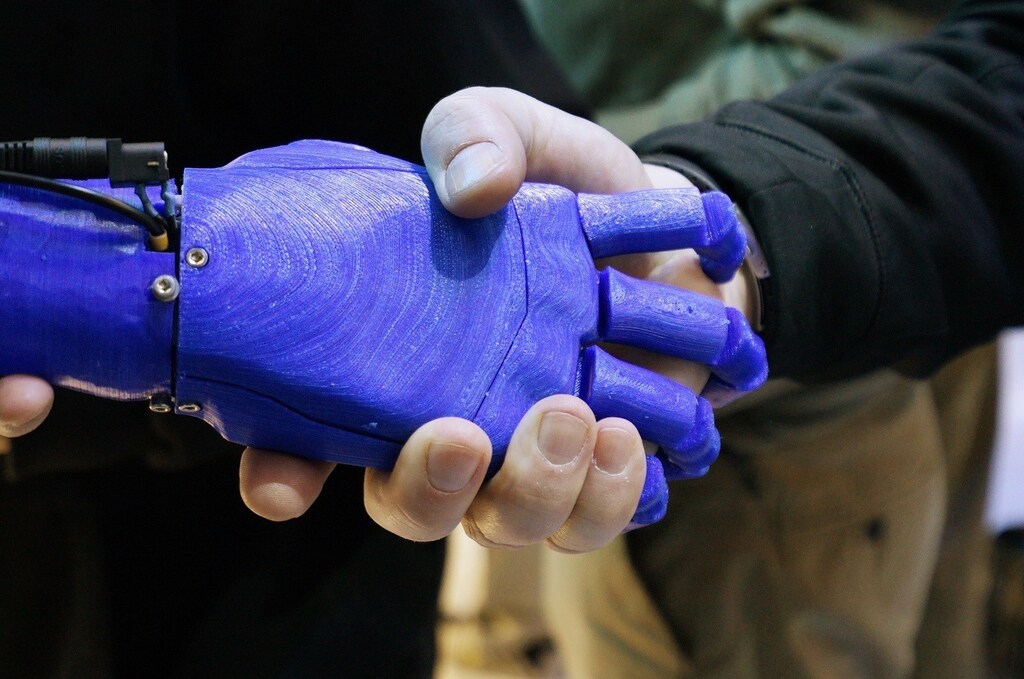 A man shakes hands with a robotic prosthetic hand in the Intel booth at the International Consumer Electronics show (CES) in Las Vegas, Nevada January 6, 2015. REUTERS/Rick Wilking (UNITED STATES - Tags: BUSINESS SCIENCE TECHNOLOGY) - RTR4KAY2