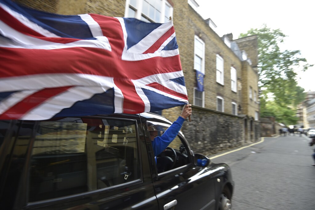 A taxi driver holds a Union flag, as he celebrates following the result of the EU referendum, in central London, Britain June 24, 2016. REUTERS/Toby Melville/File Photo - RTSNHSH