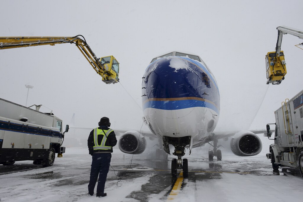 An airport staff looks on as de-icing solution are sprayed on a plane amid heavy snowfall at an airport in Urumqi, Xinjiang Uighur Autonomous Region, China, December 11, 2015. REUTERS/Stringer ATTENTION EDITORS - THIS PICTURE WAS PROVIDED BY A THIRD PARTY. THIS PICTURE IS DISTRIBUTED EXACTLY AS RECEIVED BY REUTERS, AS A SERVICE TO CLIENTS. CHINA OUT. NO COMMERCIAL OR EDITORIAL SALES IN CHINA. - RTX1YC4Q