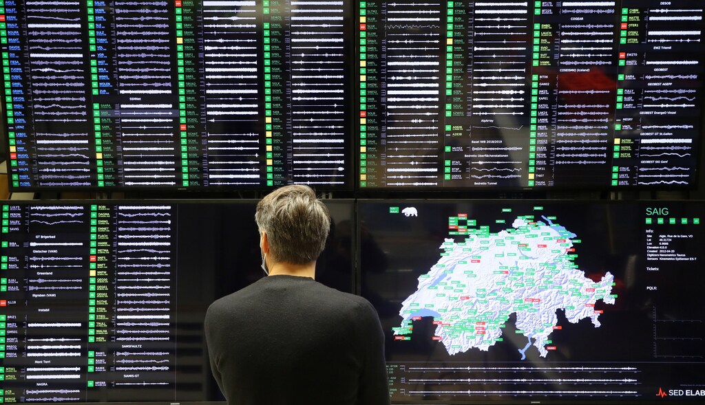 A researcher looks on a display showing a status overview of Swiss seismic stations at the Swiss Seismological Service in Zurich