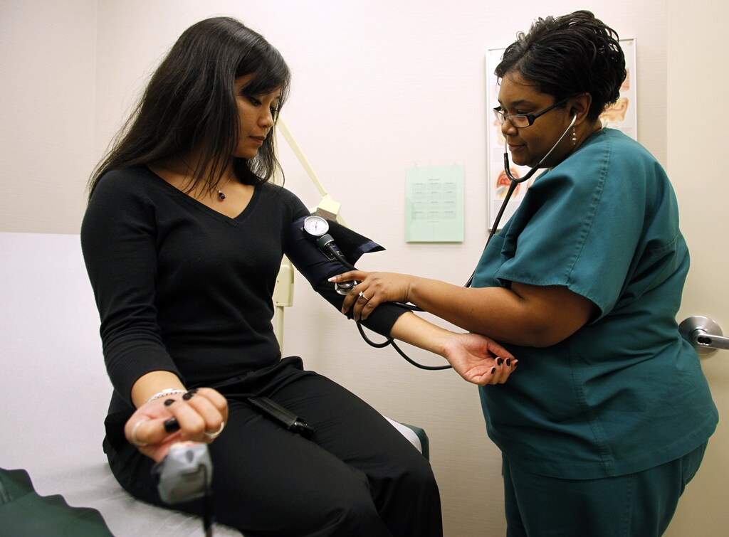 Discovery Communications Wellness Center medical technician Charline Faison checks the blood pressure of patient and Discovery employee Bonnary Lek (L) during a medical appointment at the clinic in the Discovery headquarters in Silver Spring, Maryland December 3, 2009. The parent of Animal Planet, the Discovery Channel and other major cable television channels calculates it saved $5 million since opening a corporate wellness center with a clinic and other wellness programs five years ago. About $4 million of that is from lower medical claim costs. As Democratic lawmakers in Washington inch ahead with plans to overhaul the U.S. healthcare system, companies like Discovery are striking out on their own -- whether through on-site doctors or diet plans -- to rein in soaring costs in a nation where employers still pay for the bulk of medical care. Picture taken December 3, 2009. To match Special Report USA-HEALTHCARE/WELLNESS REUTERS/Jim Bourg (UNITED STATES HEALTH BUSINESS SOCIETY) - GM1E5C90NVL01