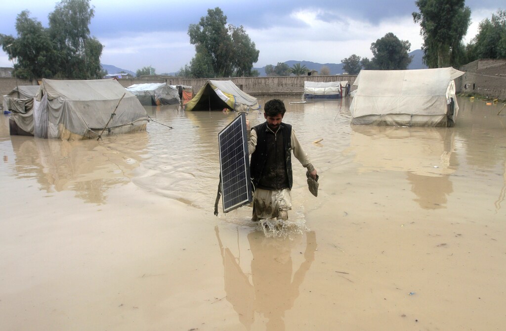 An Afghan man carries a solar panel as he wades through flood waters in the Behsud District of Nangarhar province, February 25, 2015. Four people were killed and hundred houses have been damaged after a heavy rain and flood in Nangarhar province of Afghanistan, the provincial spokesman Ahmadzia Abdulzai said. REUTERS/Parwiz (AFGHANISTAN - Tags: DISASTER ENVIRONMENT TPX IMAGES OF THE DAY) - GM1EB2P1QRM01