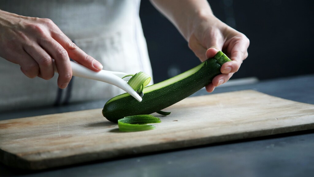 Close-up on person peeling courgette