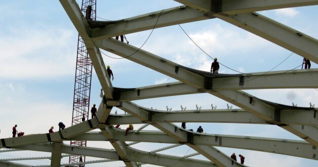 Steelworkers work on the roof structure inside the Arena Amazonia stadium, Brazil