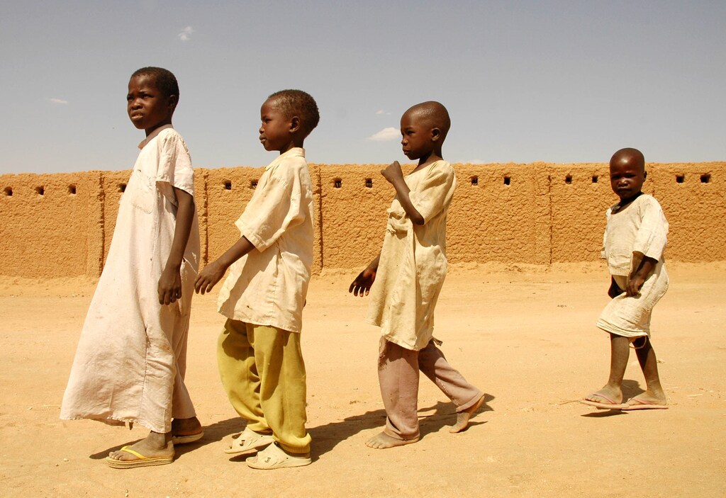 Darfur refugees walk past their school in the Gaga refugee camp in eastern Chad in this January 26, 2006 file photo. Chad's President Idriss Deby held a victory rally attended by thousands of supporters in the sun-baked capital N'Djamena on April 15, 2006 but many nervous residents feared rebels fighting to topple him may return. Insurgents bent on ending Deby's near 16-year rule over one of the world's poorest countries launched their most daring strike yet on Thursday, slipping into the dusty city at dawn before loyalist forces fought them off. Chad, which says the fighting killed more than 300 people, has accused Sudan of backing the rebels and cut diplomatic ties with Khartoum on Friday, shutting its borders and threatening to stop sheltering refugees from Sudan's Darfur region. Picture taken January 26, 2006. REUTERS/Claire Soares/Files - GM1DSJXCVSAA