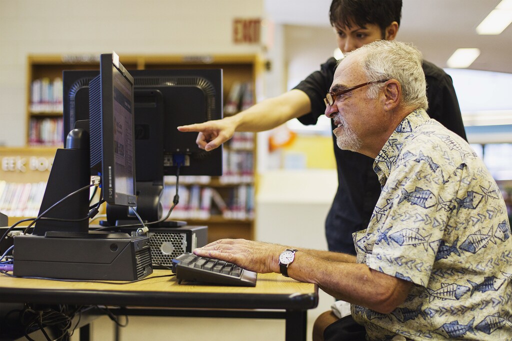 Librarian Bertrand Bobis (L) teaches a senior citizen how to use a Facebook account during a class at a branch of the New York Public Library in New York August 13, 2012. Seniors, some in their 90s, could soon be making new friends on Facebook thanks to New York libraries offering classes to help the elderly learn, or brush up their social network skills. REUTERS/Lucas Jackson (UNITED STATES - Tags: SOCIETY SCIENCE TECHNOLOGY EDUCATION) - RTR36TKI