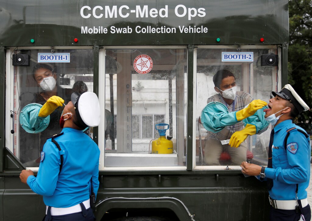 Health officials take a swab sample for the coronavirus disease (COVID-19) from traffic policemen while siting inside a mobile swab collection vehicle at Singha Durbar office complex, that houses the Prime Minister's office and other ministries, in Kathmandu, Nepal July 29, 2020. REUTERS/Navesh Chitrakar TPX IMAGES OF THE DAY - RC203I9I59DZ