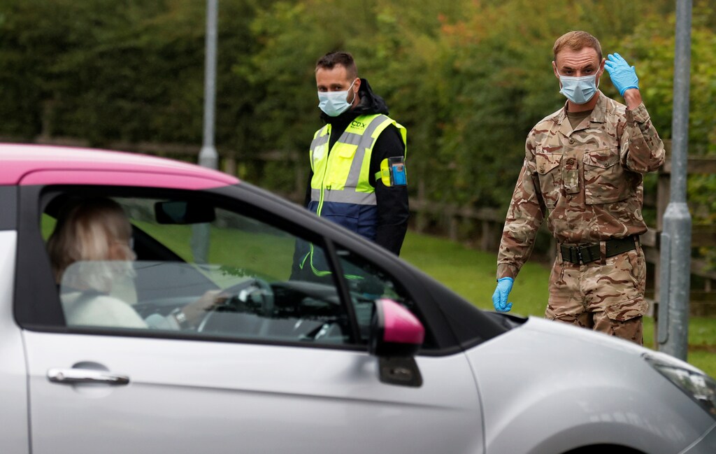 A soldier wearing a protective mask gestures as he directs cars into a coronavirus disease (COVID-19) testing center, as Blackburn with Darwen Council imposes local restrictions in an effort to avoid a local lockdown being forced upon the area, amid the coronavirus disease (COVID-19) outbreak, in Blackburn, Britain July 16, 2020. REUTERS/Phil Noble - RC2AUH9DL0IJ