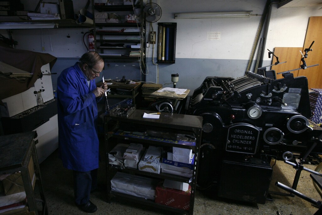 Retiree Victor Goncalves, 67, works in a printing shop at the Alfama neighborhood in Lisbon February 14, 2012. Goncalves receives a state pension of 400 euros ($525) each month but still needs to run his printing shop to support himself. Three years ago, he used to have 280 customers daily but today, he only sees 30 customers every day. REUTERS/Rafael Marchante (PORTUGAL - Tags: SOCIETY BUSINESS EMPLOYMENT) - RTR2XUSU