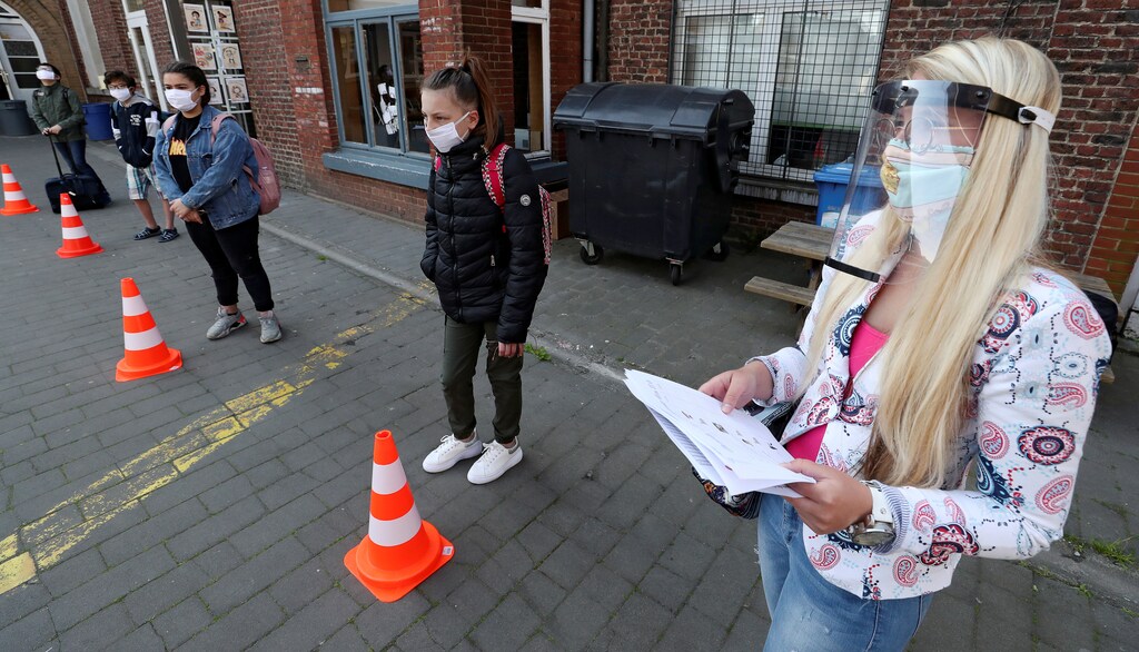 Students wearing protective face masks keep social distancing as they arrive a francophone primary school during its reopening in Jumet, as a small part of Belgian children head back to their schools with new rules and social distancing measures, during the outbreak of the coronavirus disease (COVID-19), in Jumet, Belgium, May 18, 2020. REUTERS/Yves Herman - RC2VQG99GB6P