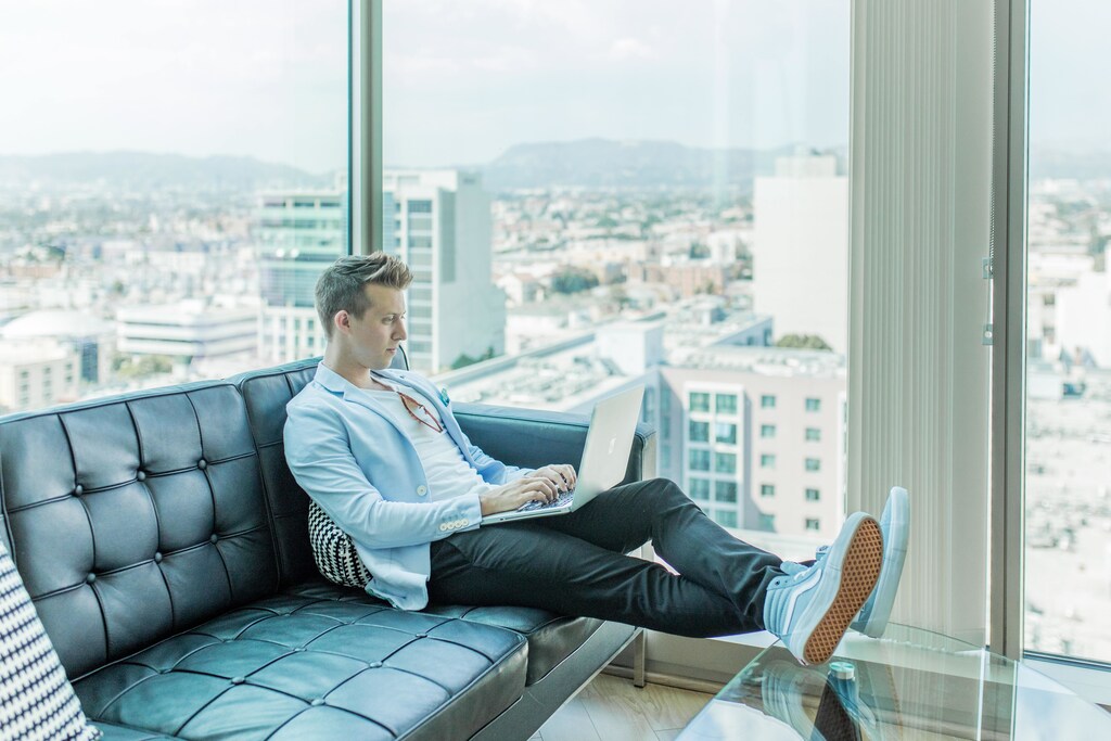 This image shows someone sitting on a sofa working on a laptop, illustrating changing working patterns