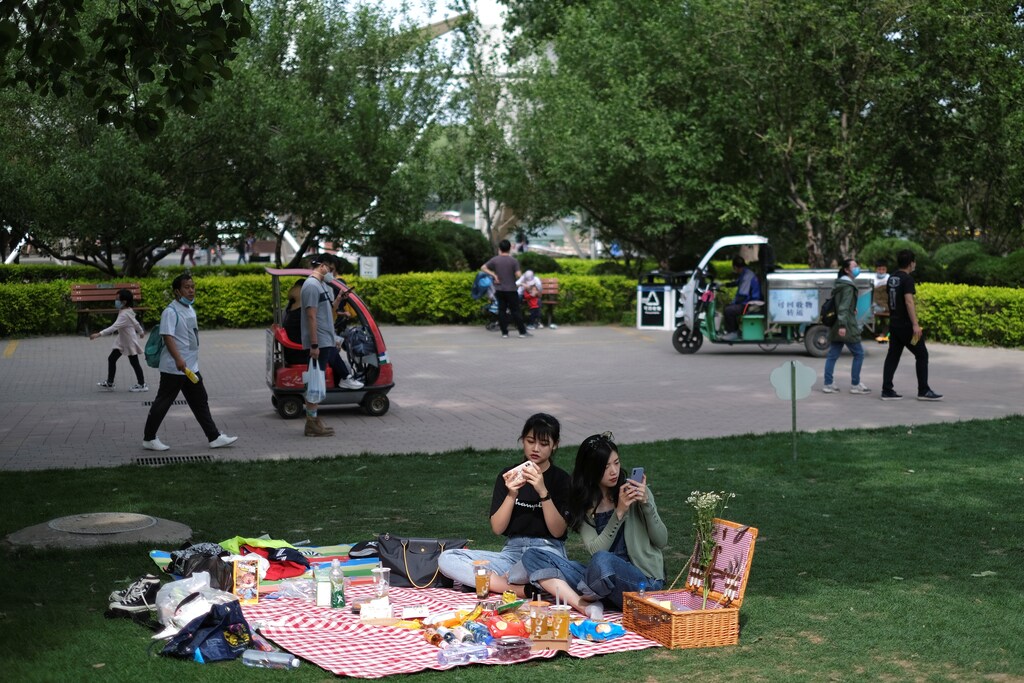 Women use their cellphones while sitting on a picnic blanket at Sun Park during Labour Day holiday, following an outbreak of the coronavirus disease (COVID-19), in Beijing, China May 5, 2020. REUTERS/Carlos Garcia Rawlins - RC2EIG9BMJD3