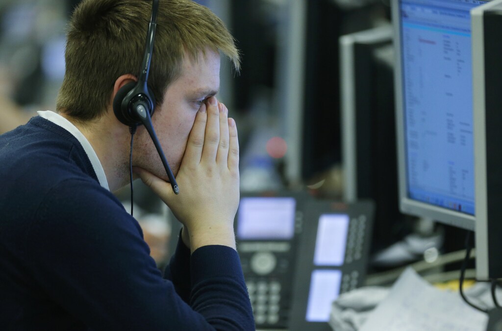 A broker at IG Index rests his face in his hands as he looks at his screens in the City of London February 25, 2013. Sterling hit a two-and-a-half year low against the dollar and a 16-month trough against the euro on Monday after ratings agency Moody's stripped the UK of one of its prized triple-A ratings, rounding off a week of woe for the currency. REUTERS/Andrew Winning (BRITAIN - Tags: BUSINESS POLITICS) - RTR3EA05