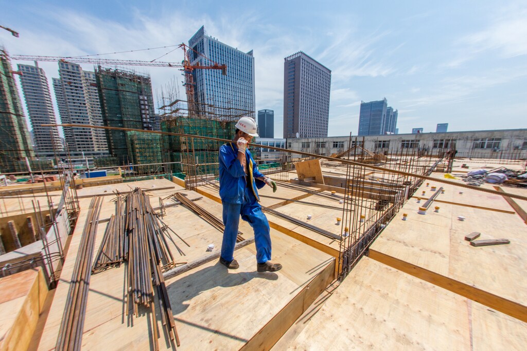 A worker carries a steel bar at a construction site of a residential building in Huzhou, China July 14, 2017. REUTERS/Stringer ATTENTION EDITORS - THIS IMAGE WAS PROVIDED BY A THIRD PARTY. CHINA OUT. NO COMMERCIAL OR EDITORIAL SALES IN CHINA. - RTX3BENS
