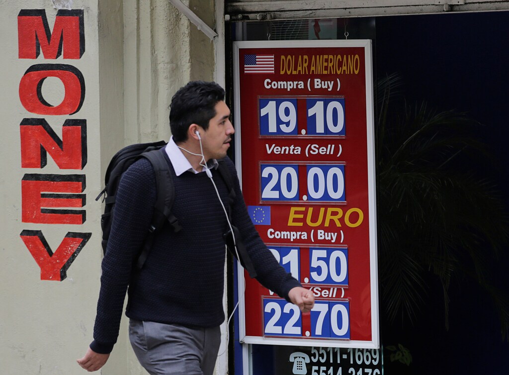 A man walks past a board displaying the exchange rates of Mexican peso against the U.S. dollar and the Euro at a foreign exchange house in Mexico City, Mexico November 17, 2016. REUTERS/Henry Romero - RTX2U57M