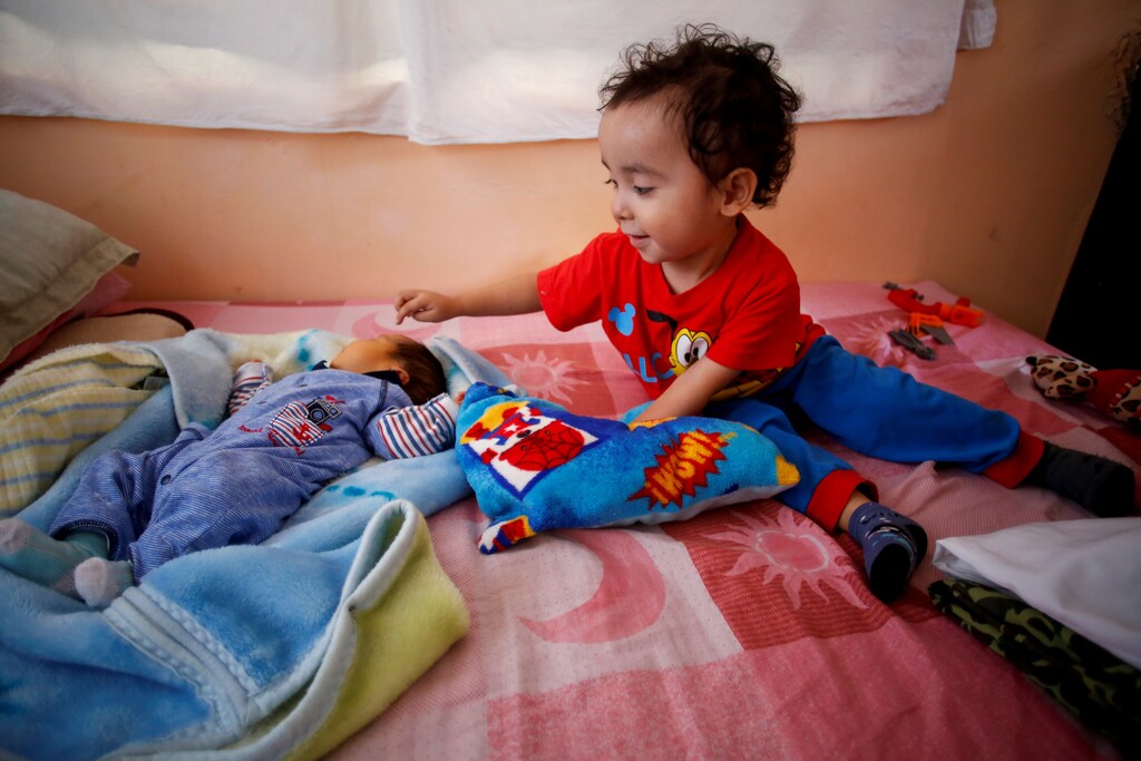 Angel Flores Lopez, 3, points to his newborn baby brother Sabino Yoehi Flores Lopez as they sit on a bed at their grandparent's apartment, where they are staying with their parents after their mother Karla Lopez Rangel gave birth to Sabino at home during the coronavirus disease (COVID-19) outbreak, in Iztapalapa, Mexico City, Mexico, June 4, 2020. REUTERS/Gustavo Graf SEARCH "COVID-19 MEXICO BIRTH" FOR THIS STORY. SEARCH "WIDER IMAGE" FOR ALL STORIES. - RC2ACH9NFQHS