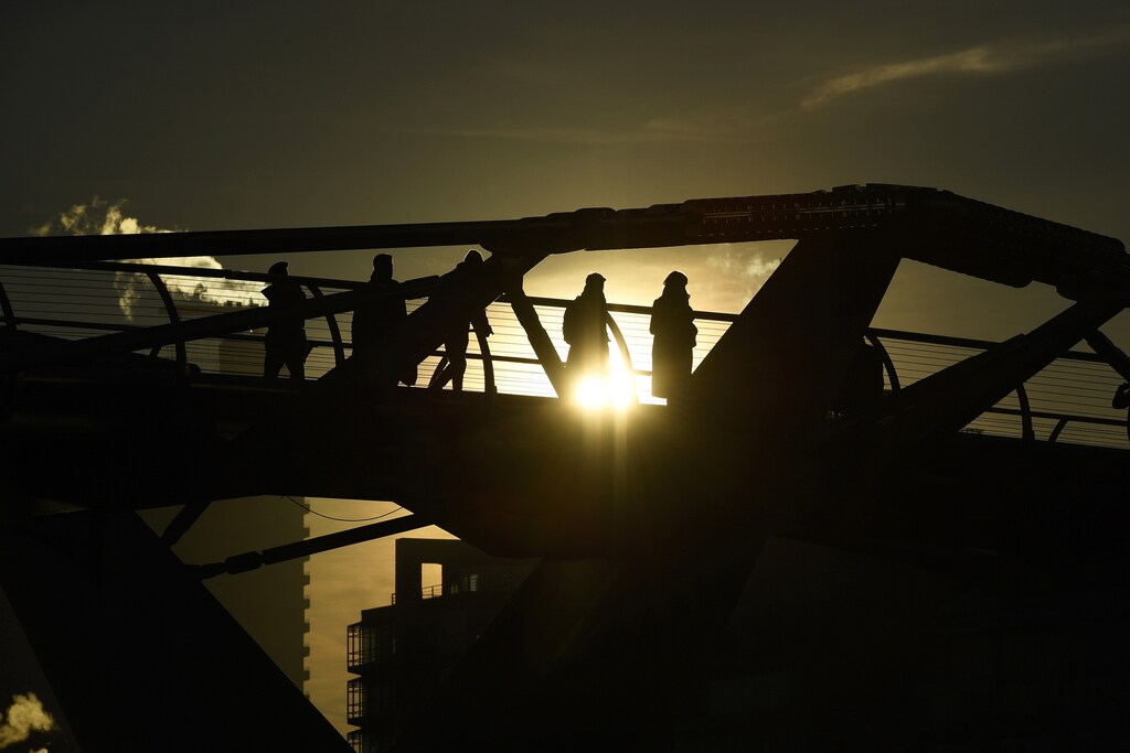 Commuters make their way across the Millennium Bridge as the sun rises over London, Britain November 30, 2016.